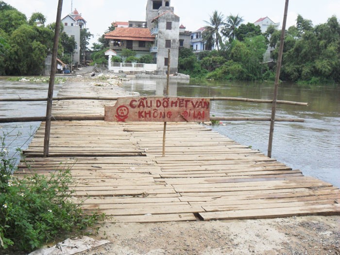 Ở gần đó, có một chiếc cầu gỗ để phục vụ người dân đi lại, nhưng đang vào mùa nước to nên cũng bị cấm đi lại.